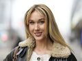 Ida Nowakowska z długimi, blond włosami, uśmiecha się w miejskim otoczeniu, w ciepłej kurtce.