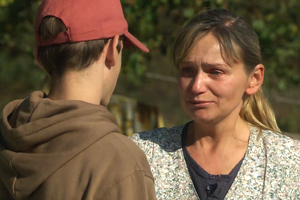 Kobieta w bluzie z dekoltem rozmawia z młodym mężczyzną, wygląda na wzruszoną.