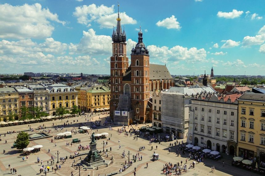 Rynek Główny w Krakowie z Kościołem Mariackim i tłumem ludzi w słoneczny dzień.