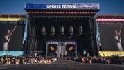 Opis ALT: Scena festiwalowa z wielkimi ekranami, tłum publiczności czeka na występ artysty.
