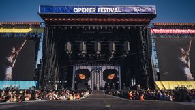 Opis ALT: Scena festiwalowa z wielkimi ekranami, tłum publiczności czeka na występ artysty.