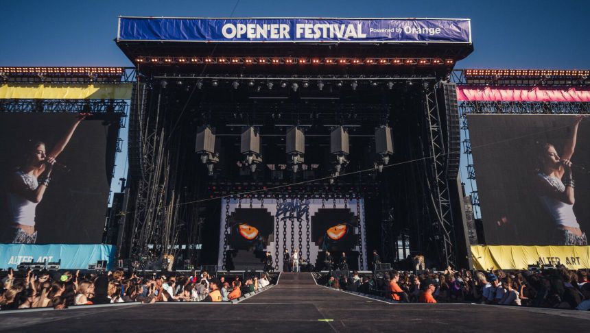 Opis ALT: Scena festiwalowa z wielkimi ekranami, tłum publiczności czeka na występ artysty.