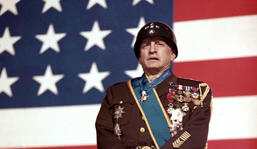 George C. Scott w filmie „Patton” w mundurze na tle amerykańskiej flagi