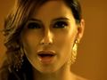 Na zdjęciu znajduje się uśmiechnięta Nelly Furtado z długimi włosami w stylowej biżuterii.
