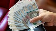 Na zdjęciu widać dłoń trzymającą banknoty o wartości 500 złotych, obok portfel.