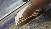 Zbliżenie na rękę trzymającą pieniądze w euro, na tle kamiennego blatu.
