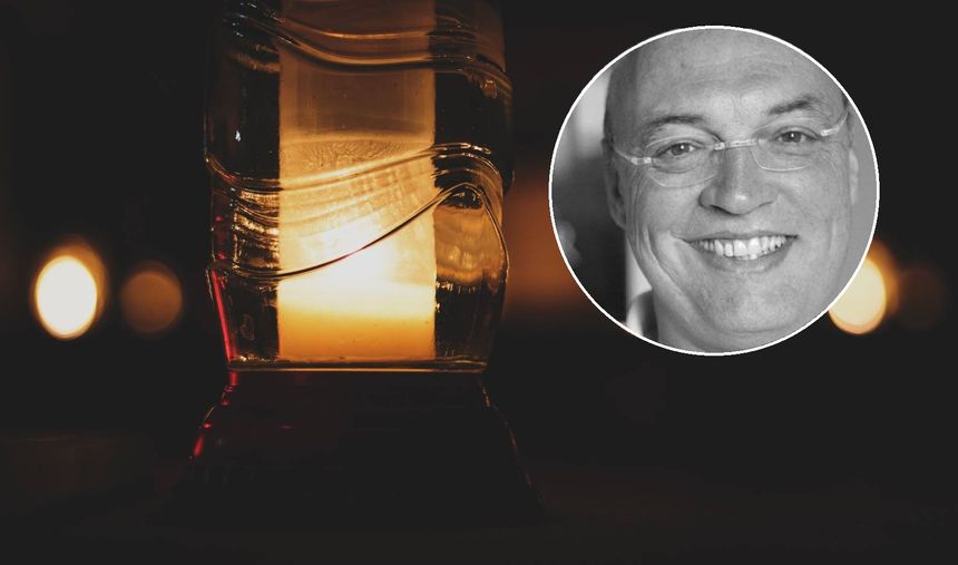 Świeca w lampionie na tle mrocznego tła, w rogu zdjęcia uśmiechnięty mężczyzna.