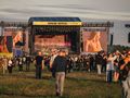 Tłum ludzi na festiwalu Open'er, widok na scenę z dużymi ekranami.