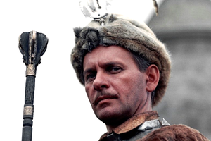 Mężczyzna w futrzanej czapce, trzymający berło, w tle zamek. Historyczny lub filmowy motyw.