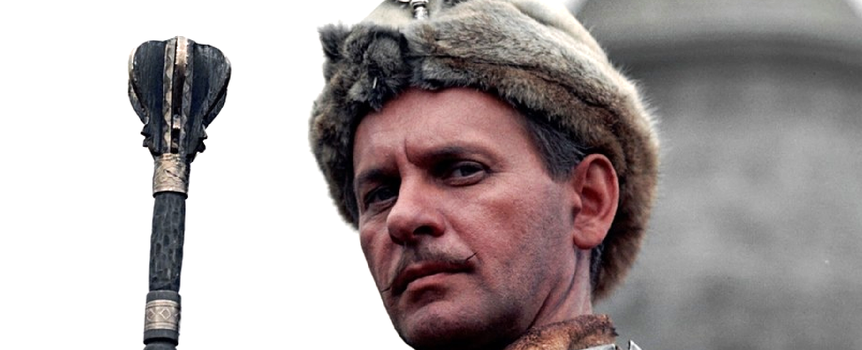 Mężczyzna w futrzanej czapce, trzymający berło, w tle zamek. Historyczny lub filmowy motyw.