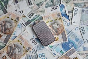 Na zdjęciu widać banknoty polskich złotych oraz metalowy przedmiot.