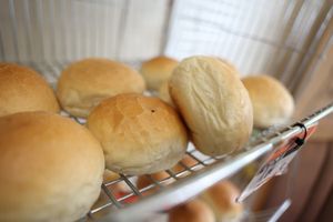 Puszyste bułki na metalowej półce, w różnych kształtach i kolorach.