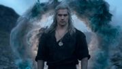 Mężczyzna z długimi, siwymi włosami, w czarnej koszuli, stoi przed magiczną chmurą.
