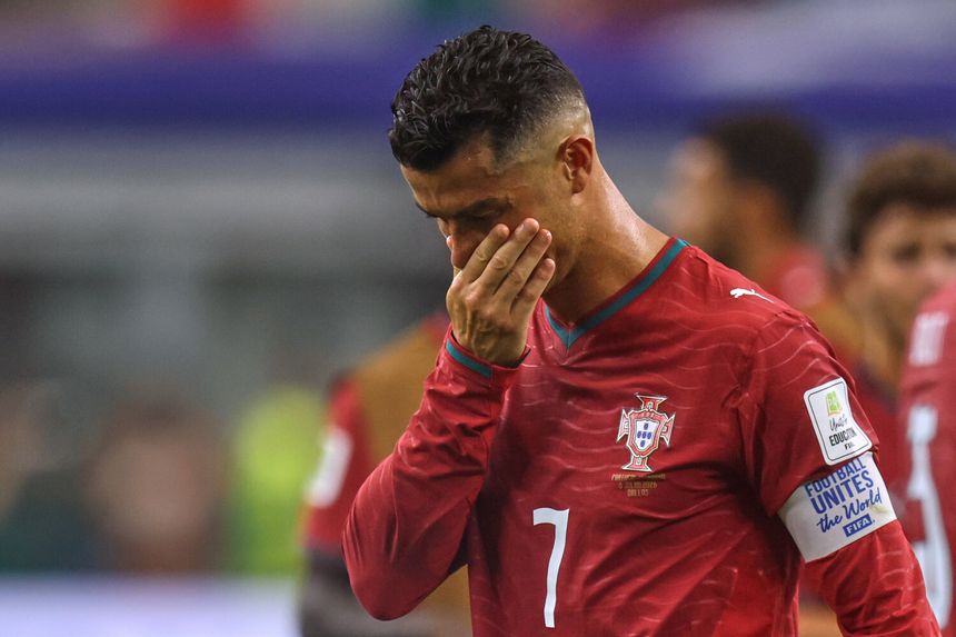 Cristiano Ronaldo w czerwonym stroju z logo Portugalii, smutny po przegranej. Wygląda na rozczarowanego.