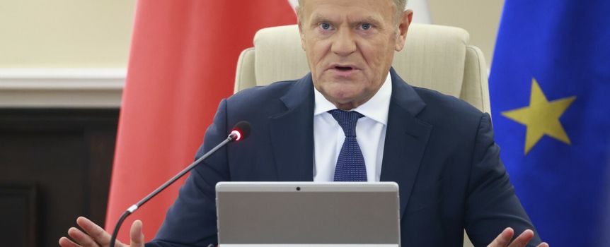 Na zdjęciu Donald Tusk przemawia podczas spotkania, z rękami uniesionymi przed sobą.