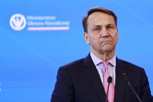 Mężczyzna w garniturze, z poważnym wyrazem twarzy, przemawia na konferencji.