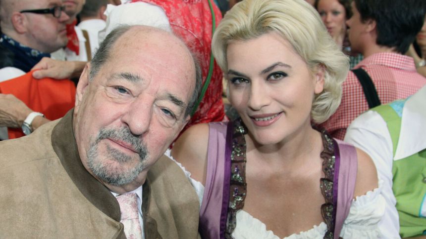 Na zdjęciu uśmiechnięty mężczyzna i kobieta w tradycyjnych strojach, w tle ludzie podczas wydarzenia.