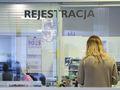 Na zdjęciu widoczna jest osoba w recepcji, z napisem 