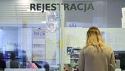 Na zdjęciu widoczna jest osoba w recepcji, z napisem 
