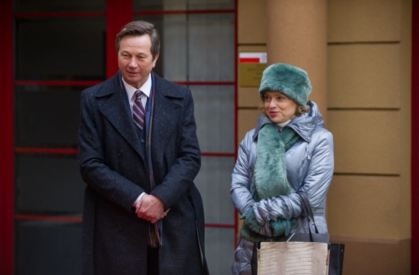 Dwoje ludzi na zewnątrz, ubranych w ciepłe płaszcze, stojących obok siebie.