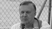 Karol Stopa z mikrofonem w ręku, ubrany w biały T-shirt, z siatką w tle.