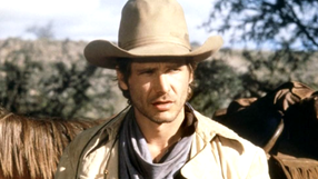 Harrison Ford w kapeluszu i płaszczu, tło górzyste, widok na konie.