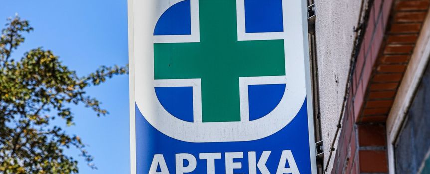 Znak apteki: zielony krzyż na niebieskim tle z napisem 