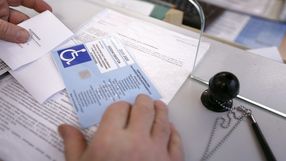 Na stole widoczne dokumenty, w tym karta parkingowa dla osób niepełnosprawnych.