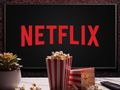 Na ekranie widać logo Netflixa, obok miski popcornu i pilota do telewizora.
