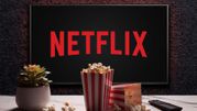 Na ekranie widać logo Netflixa, obok miski popcornu i pilota do telewizora.