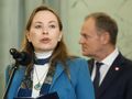 Kobieta z mikrofonem w ręku, w tle mężczyzna w garniturze. Rozmowa w poważnej atmosferze.