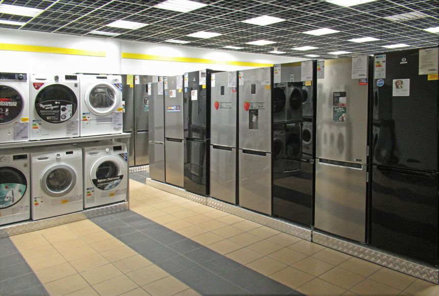 Sklep z urządzeniami agd: lodówki i pralki w rządku na jasnej podłodze.