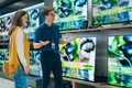 Mężczyzna i kobieta w sklepie z elektroniką oglądają telewizory na wystawie.