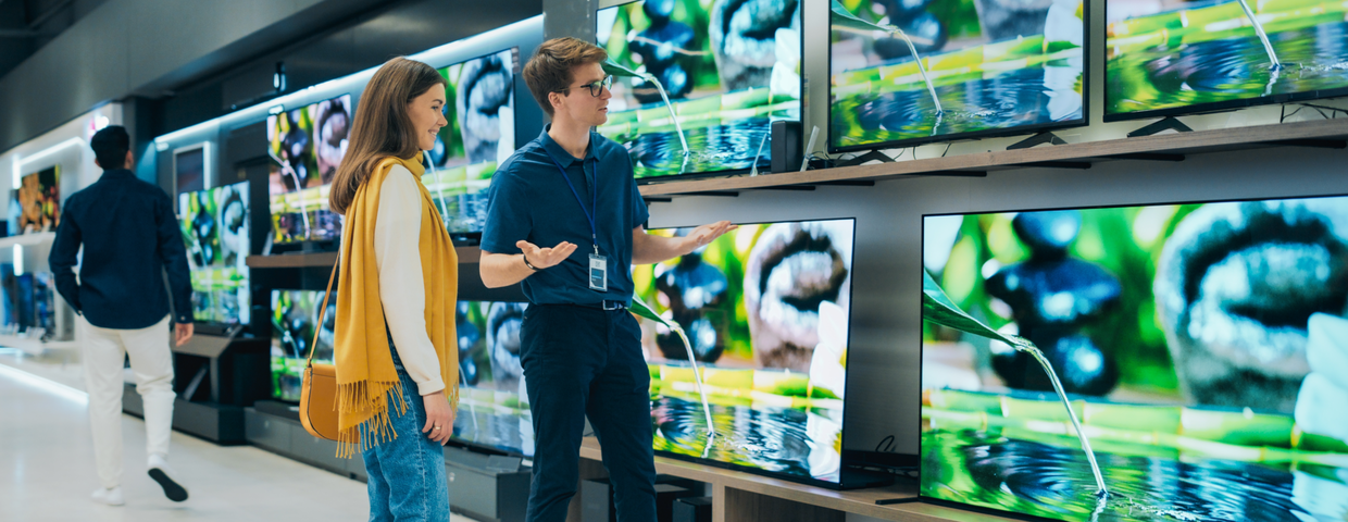 Mężczyzna i kobieta w sklepie z elektroniką oglądają telewizory na wystawie.
