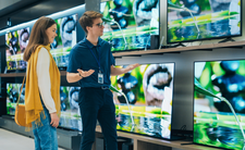 Mężczyzna i kobieta w sklepie z elektroniką oglądają telewizory na wystawie.