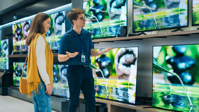Mężczyzna i kobieta w sklepie z elektroniką oglądają telewizory na wystawie.