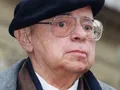 Mężczyzna w okularach i czapce, z poważnym wyrazem twarzy, stoi na zewnątrz.