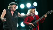 Dwaj mężczyźni na scenie, jeden z mikrofonem, drugi gra na gitarze elektrycznej.