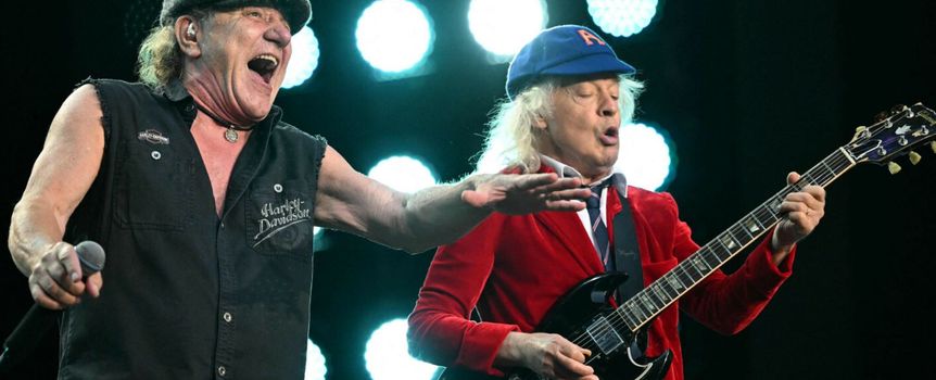 Dwaj mężczyźni na scenie, jeden z mikrofonem, drugi gra na gitarze elektrycznej.
