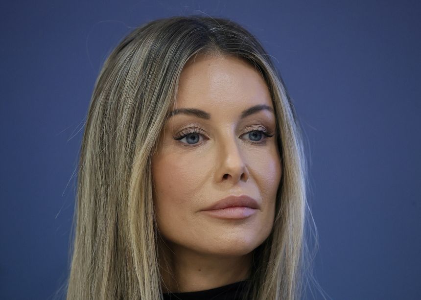 Na zdjęciu: Małgorzata Rozenek-Majdan z długimi, jasnymi włosami, patrząca w dal na tle niebieskiej ściany.