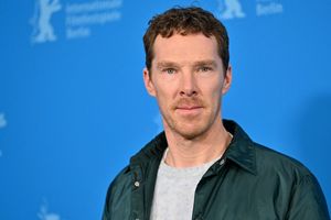 Mężczyzna w jasnej bluzie i ciemnej kurtce stoi na tle niebieskiej ścianki z logo Berlinale.