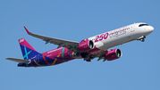 Samolot Wizz Air w kolorowym malowaniu, przelatujący na tle błękitnego nieba.