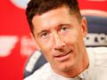Na zdjęciu Robert Lewandowski, uśmiechający się na tle czerwonej ściany.