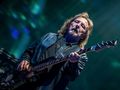 Geezer Butler. Mężczyzna gra na gitarze basowej, w tle kolorowe światła estrady.