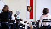 Sala z uczestnikami, w tle flaga Polski z godłem. Nauczycielka z przodu.