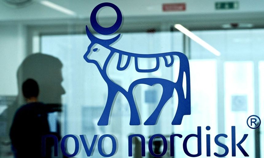 Logo firmy Novo Nordisk z niebieską krową i okręgiem na tle przeszklonej ściany.