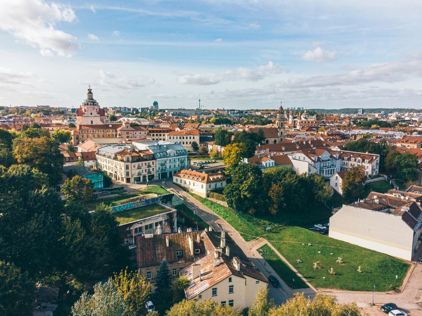 Widok na miasto z zielenią, zabytkowymi budynkami i błękitnym niebem.