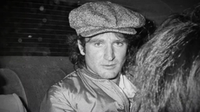 Robin Williams. Na zdjęciu mężczyzna w czapce z dzianiny, siedzący w samochodzie, wygląda na zamyślonego.