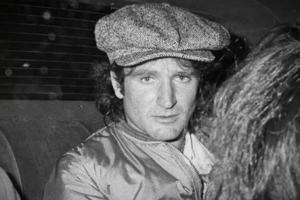 Robin Williams. Na zdjęciu mężczyzna w czapce z dzianiny, siedzący w samochodzie, wygląda na zamyślonego.
