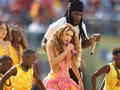 Na scenie tańczą i śpiewają artyści w kolorowych strojach, w tym Shakira.